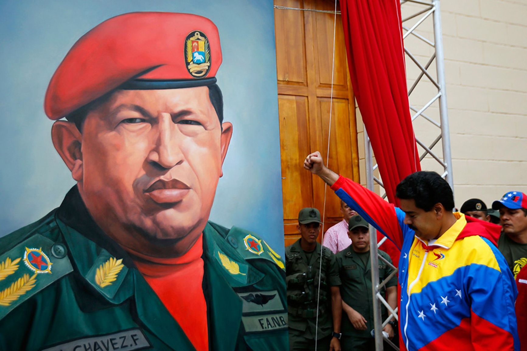A Venezuelan soldier stands by a portrait of Hugo Chávez